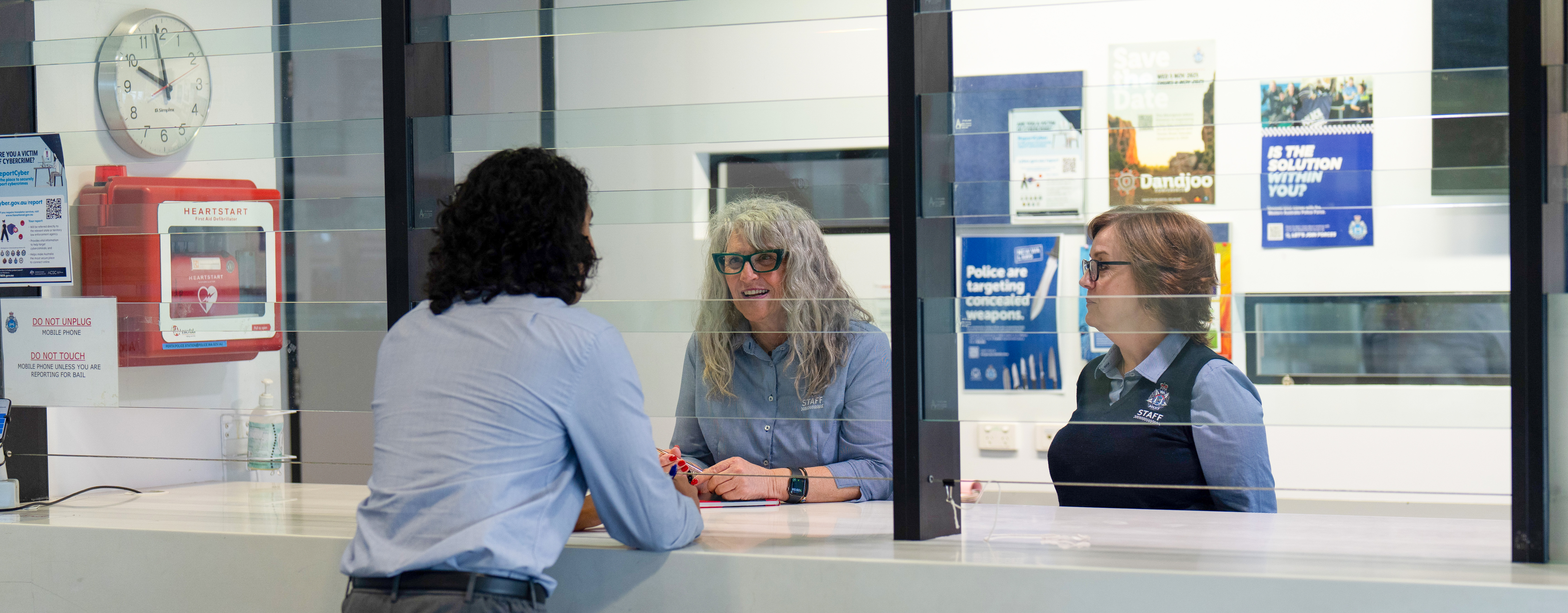 Two people behind a desk offering help to a customer