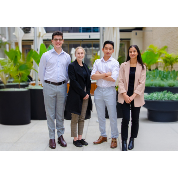 four young adults standing in an office smiling